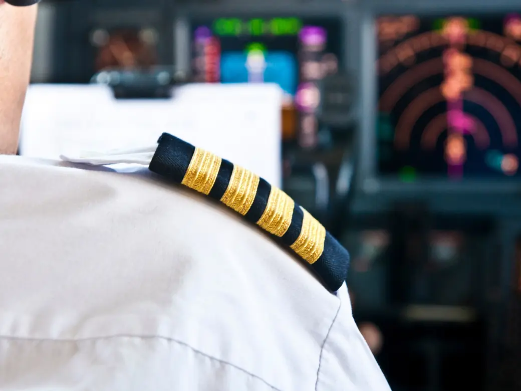 The shoulder of an airplane pilot in front of radar equipment