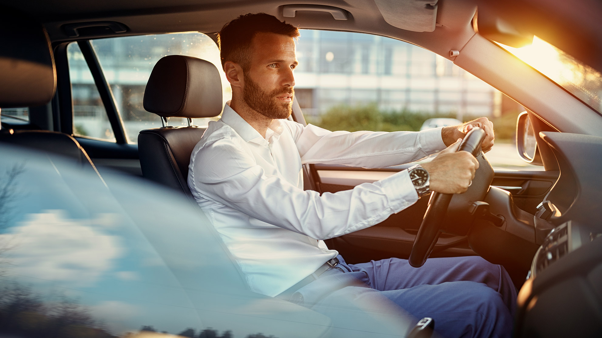 Young businessman in suit driving an empty car in traffic