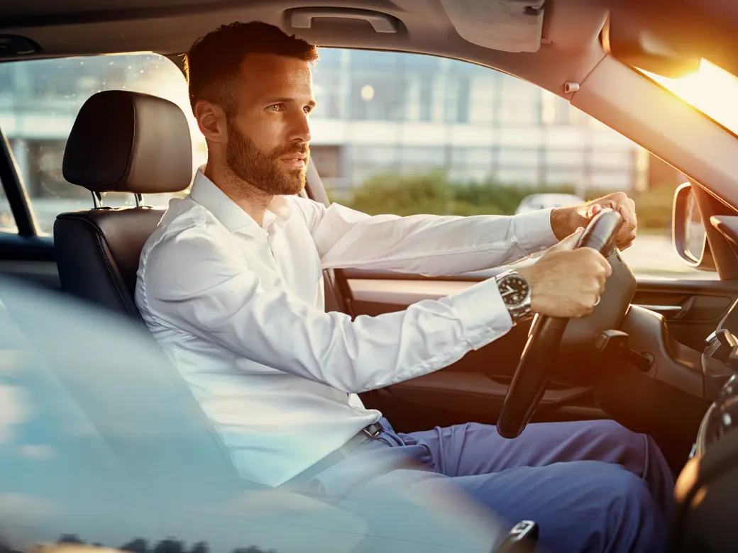 Young businessman in suit driving an empty car in traffic