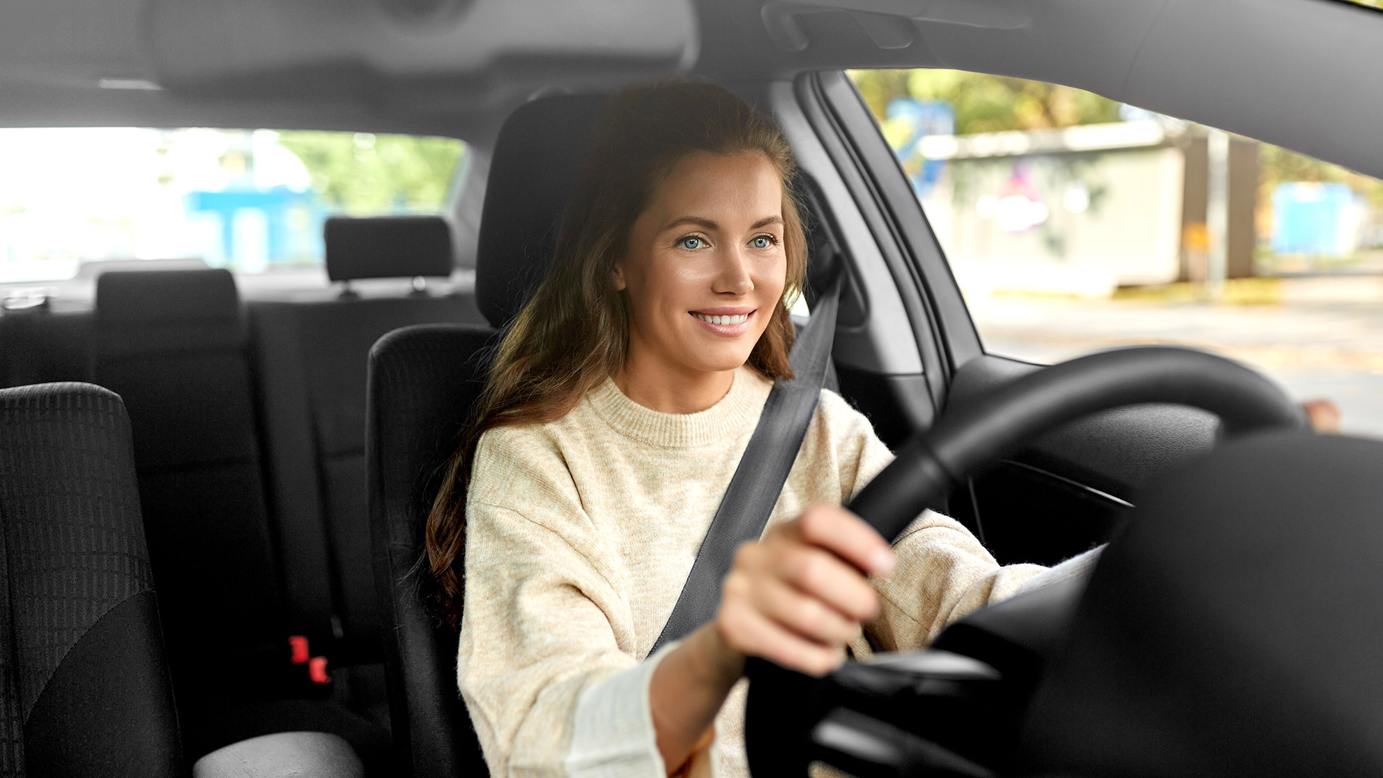 Young smiling woman driving an empty car and driving in traffic 