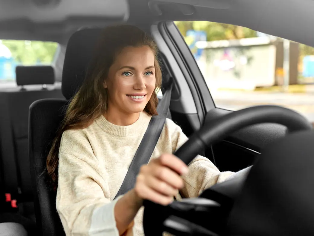 Young smiling woman driving an empty car and driving in traffic 